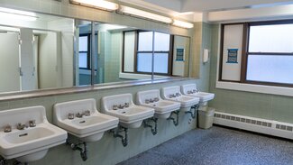Communal bathroom with row of sinks and large mirror