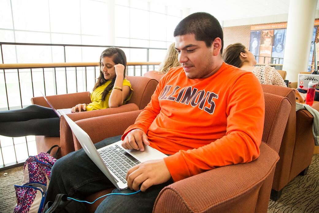Student wearing Illinois tshirt using laptop