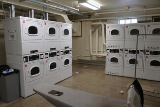 Allen Hall laundry room with stacked dryers and ironing board