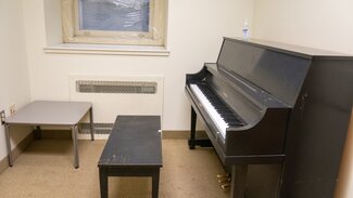 Music practice room with piano, bench and table