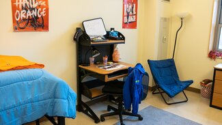 Foot of bed, desk with rolling chair, comfy chair, and Illini decorations