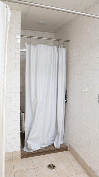 Single occupancy accessible bathroom shower with curtain