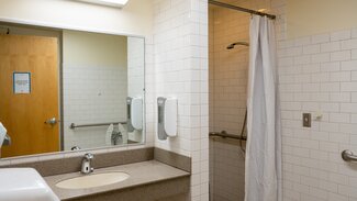 Single occupancy accessible bathroom with shower, sink and hand rails